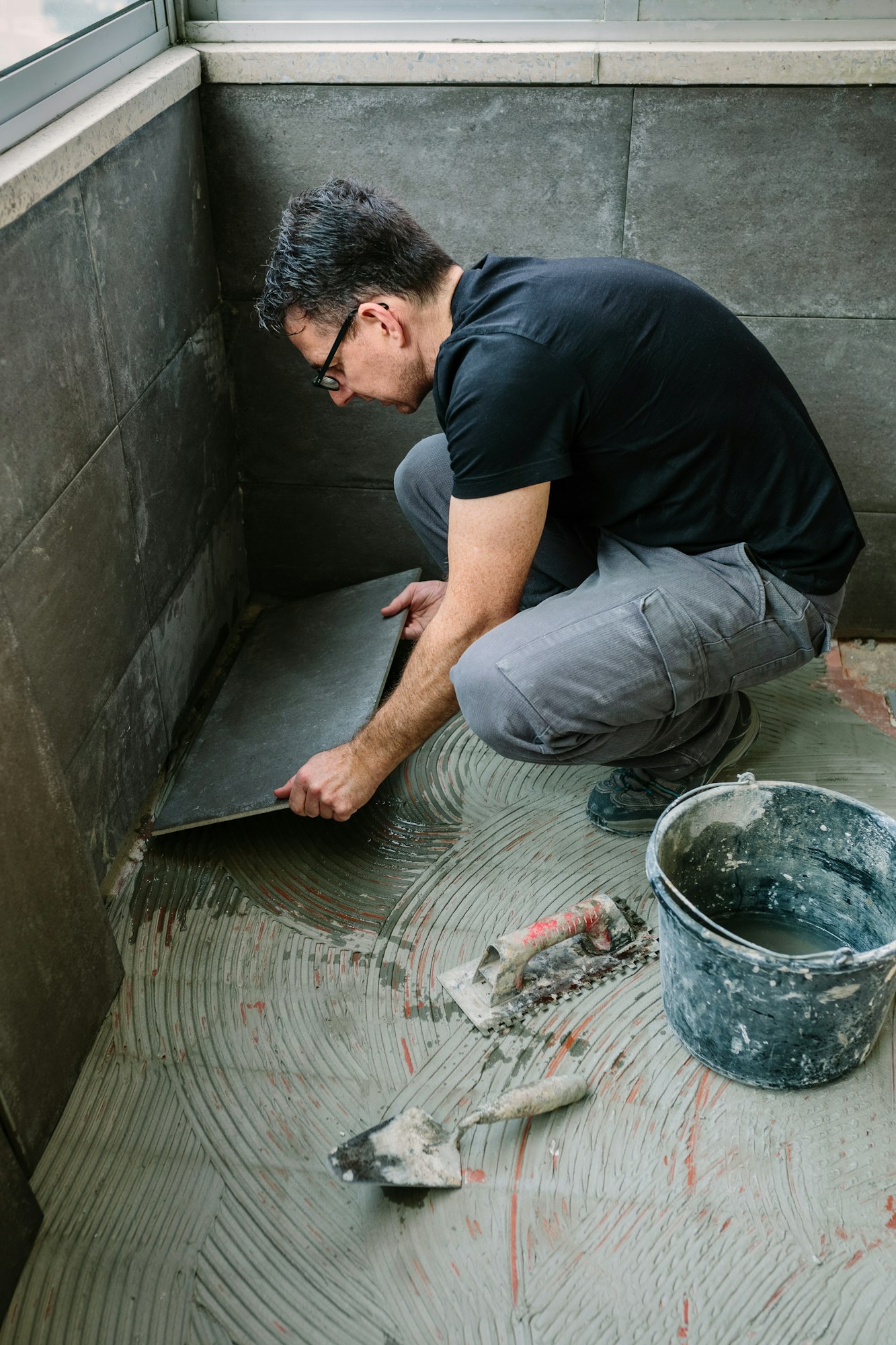 Workman laying tiles on a terrace